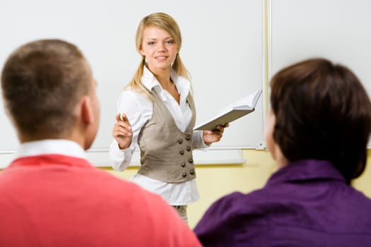 Image of clever teacher with book in hand explaining something to the students at the lesson