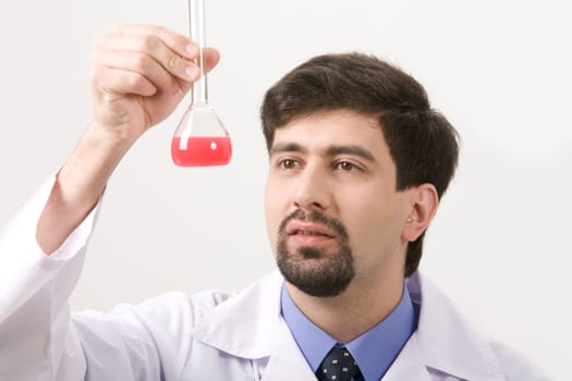 Portrait of medical specialist looking at flask on a white background