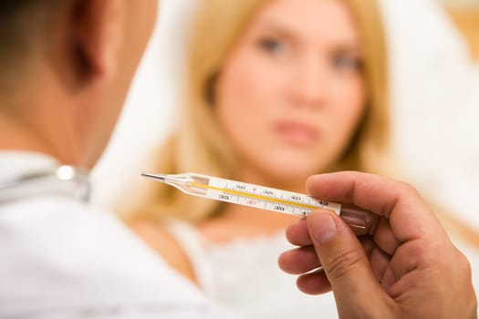 Close-up of doctors hand holding thermometer with sick woman on background