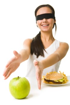 Portrait of young girl with her eyes folded stretching her arms towards green apple