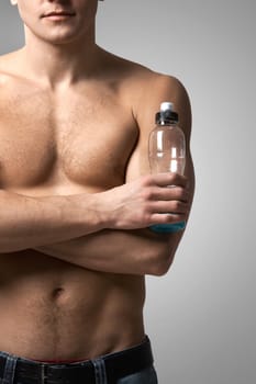 Image of handsome man with bare torso holding bottle of water