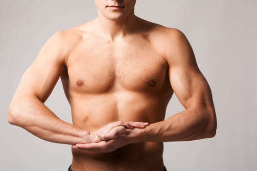 Image of shirtless man keeping his arms by chest