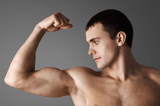 Close-up of strong muscular man over grey background