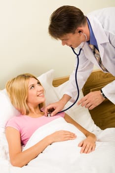 Image of sick young woman lying in bed and being examined by therapeutist