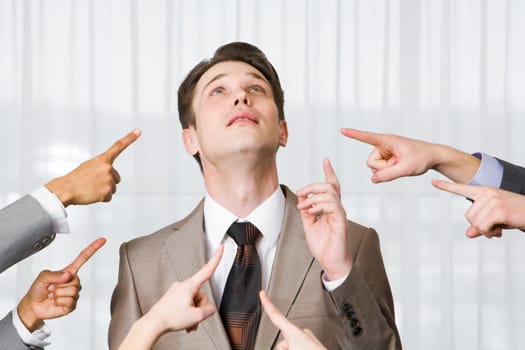 Inquiring businessman pointing upwards surrounded by several forefingers