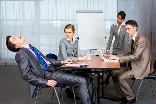 Photo of displeased businesspeople looking sternly at snoring man at presentation