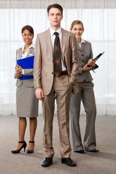 Three business partners looking at camera with successful man in front