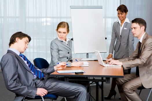 Photo of businesspeople looking sternly at their sleeping colleague at presentation