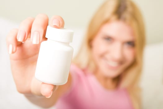Close-up of females hand holding plastic pill bottle containing vitamins