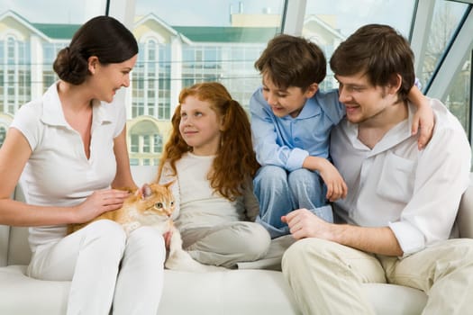Portrait of careful parents and their two children enjoying weekend day at home