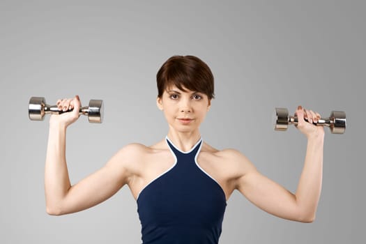Image of smiling woman exercising with barbells in hands