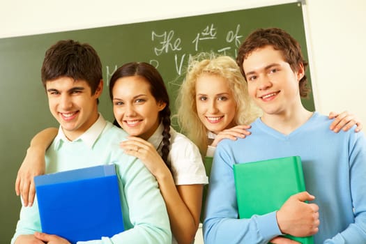Portrait of happy students standing next to each other and looking at camera with smiles