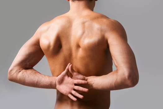 Back view of shirtless man keeping his hands behind back