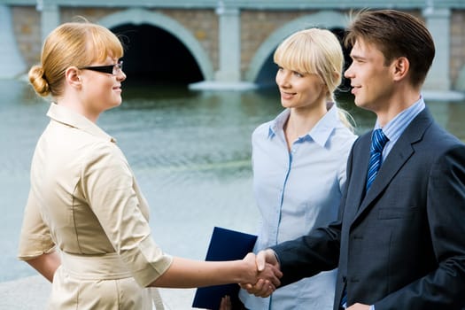 Portrait of business partners handshaking at meeting and looking at each other