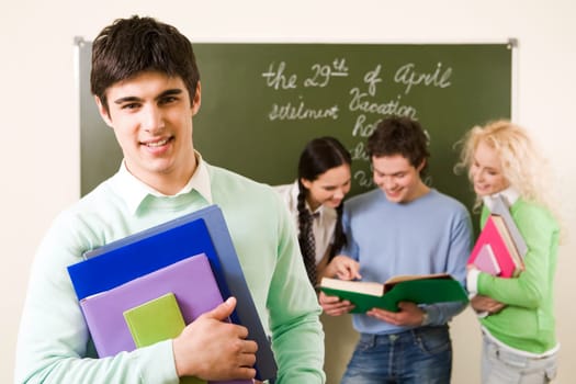 Portrait of successful student with textbooks in hands on background of reading groupmates