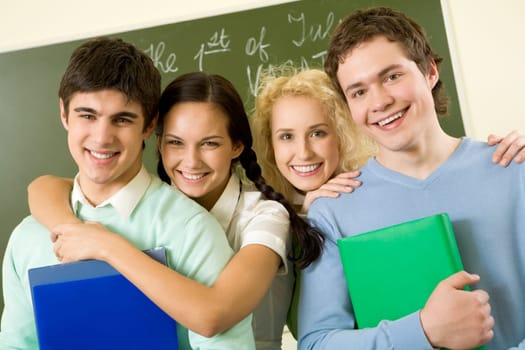 Portrait of happy students standing next to each other and looking at camera with smiles