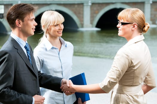 Portrait of business partners handshaking at meeting and looking at each other