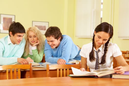 Portrait of smart students discussing book with smart girl at foreground