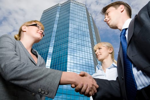 View from below of successful businesspeople handshaking as symbol of collaboration