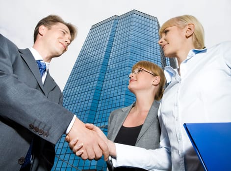 Below view of happy business partners congratulating each other on making an agreement by handshake