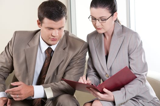 Portrait of businessman and lady communicating while looking at document in the office
