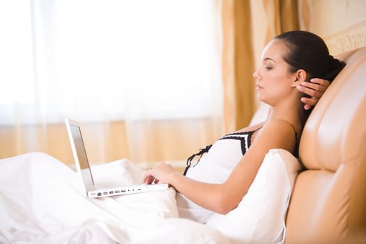 Image of pretty girl looking at laptop monitor while in bed
