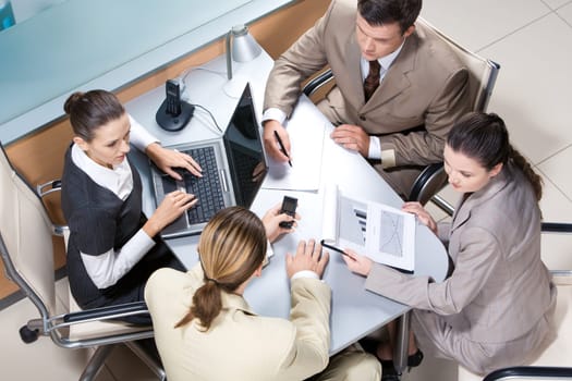 Portrait of four professionals sitting at the table and discussing business ideas in the office