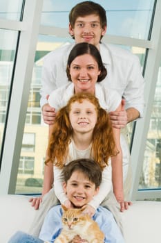 Photo of cheerful children and their parents looking at camera on each others heads