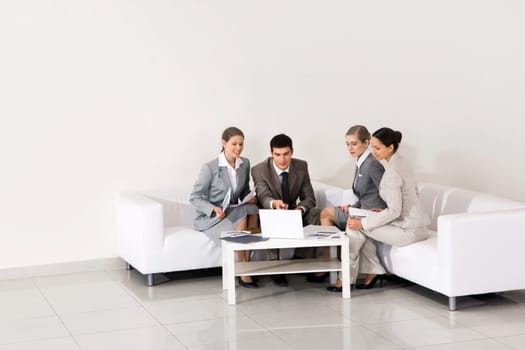 Portrait of friendly workteam looking at laptop monitor being pointed at by smart employer