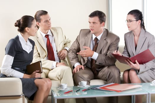 Portrait of serious business people sitting next to each other and communicating at business meeting