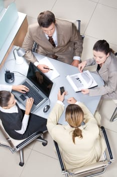Above view of working business group sitting at table during corporate meeting