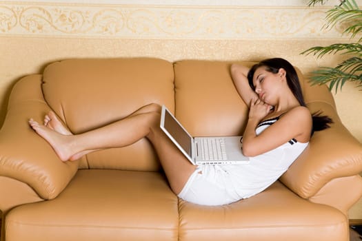 Image of pretty girl sleeping with laptop on leather sofa