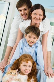 Photo of cheerful children and their parents looking at camera with smiles