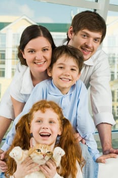Photo of happy family members and their cute cat having fun