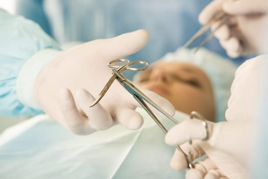 Close-up of medical instrument being passed over by assistant to surgeon