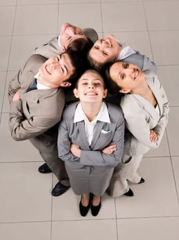 Above view of several business partners looking upwards at camera with their heads close to each other