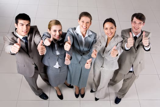 Above view of several successful partners looking at camera and showing thumbs up