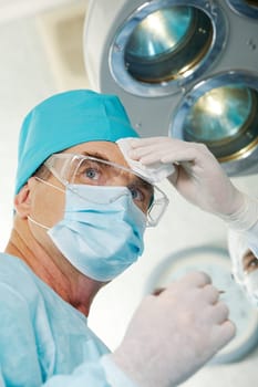 Image of surgeon during work with his forehead being rubbed by nurse