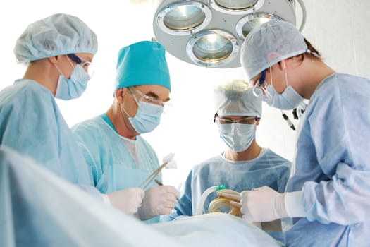 Several surgeons surrounding patient on operation table during their work