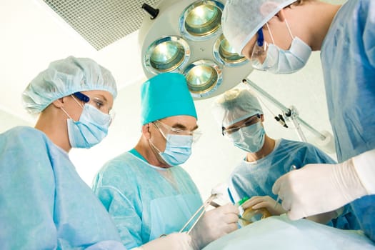 Group of surgeons looking at patient on operation table during their work