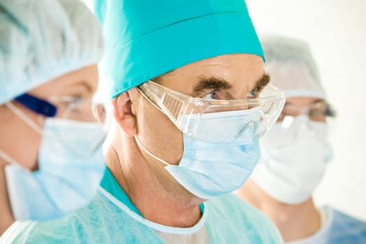 Portrait of senior doctor looking aside between two assistants