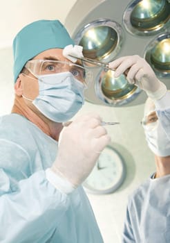 Portrait of tired doctor in special wearing and nurse wiping his forehead