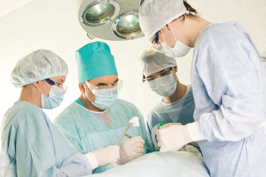 Several surgeons surrounding patient on operation table during their work