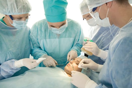 Image of surgeons near operation table with patient on it during operation