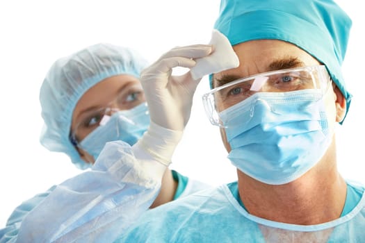 Image of surgeon during work with his forehead being rubbed by nurse