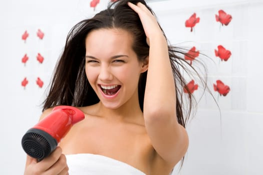 Photo of joyful female drying her hair after washing it