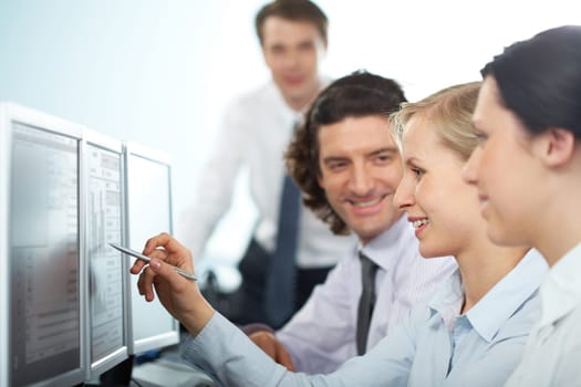 Businesswoman pointing at computer monitor showing it to her colleagues