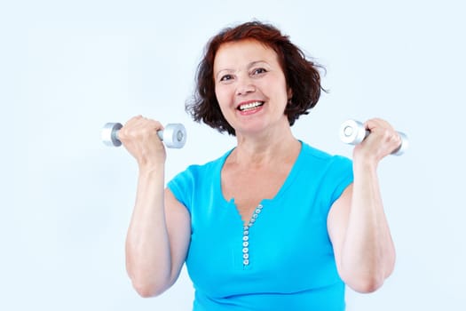 Portrait of middle-aged female doing physical exercise with dumbbells