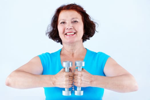 Portrait of middle-aged female doing physical exercise with dumbbells