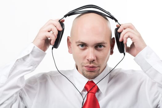 Portrait of serious male putting headphones on his head and looking at camera